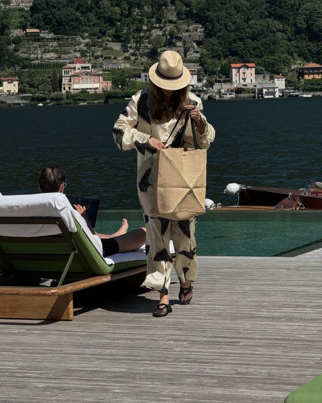 vikyrader wearing KHAITE Minta printed twill shirt, ALAIA Black BALLET FLATS IN FISHNET and LOEWE + Paula's Ibiza Puzzle Fold large leather-trimmed raffia tote.